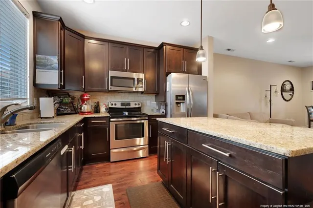 a kitchen with stainless steel appliances granite countertop wooden cabinets a stove top oven a sink and dishwasher