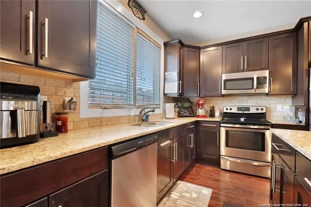 a kitchen with stainless steel appliances granite countertop a sink a stove and cabinets
