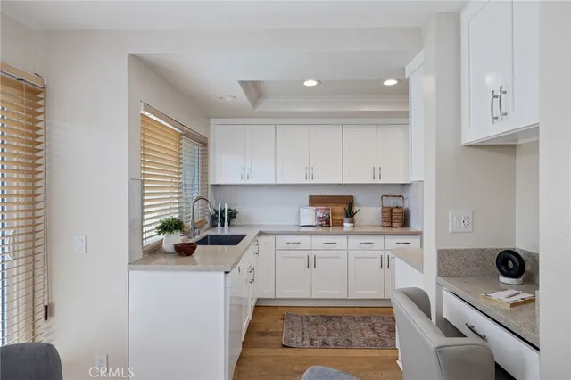 a kitchen with stainless steel appliances a refrigerator a sink a stove and white cabinets with wooden floor