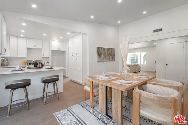 a open dining room with stainless steel appliances kitchen island granite countertop a table chairs and a refrigerator