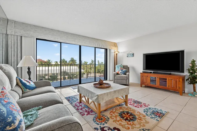 a living room with furniture a flat screen tv and a floor to ceiling window