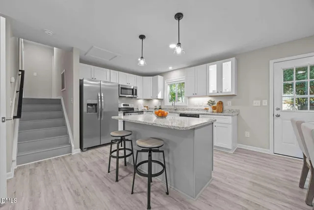 a kitchen with stainless steel appliances a refrigerator a sink dishwasher a stove and white countertops with wooden floor