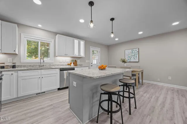 a kitchen with granite countertop a stove a sink a window and chairs