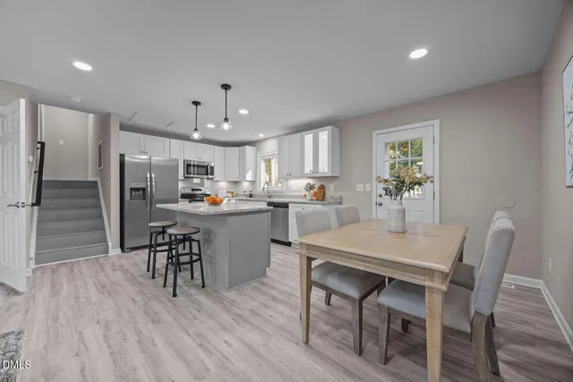 a kitchen with a dining table chairs refrigerator and cabinets