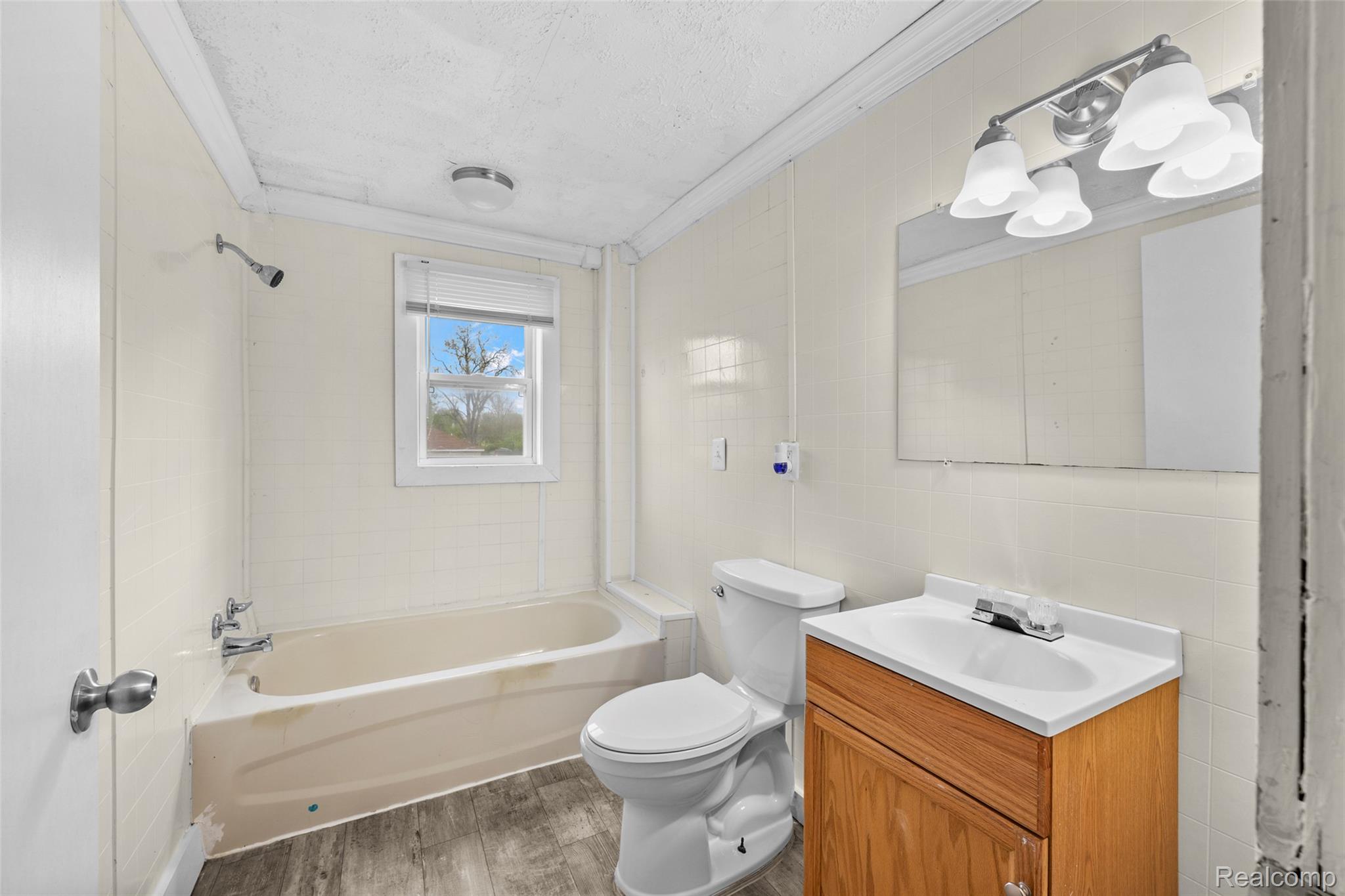3605 Ash Street Inkster, MI 48141 - Photo 20 of 25 Bathroom featuring vanity, tile walls, light wood finished floors, ornamental molding, and washtub / shower combination