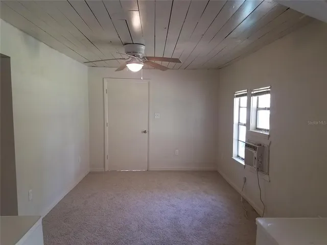 an empty room with chandelier fan and windows