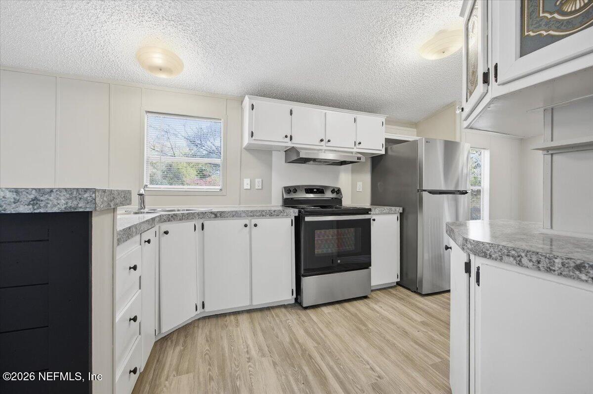 5621 Willow Road Macclenny, FL 32063 - Photo 6 of 15 a kitchen with granite countertop a sink stainless steel appliances and white cabinets
