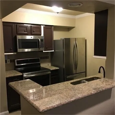 a kitchen with granite countertop a refrigerator and a sink