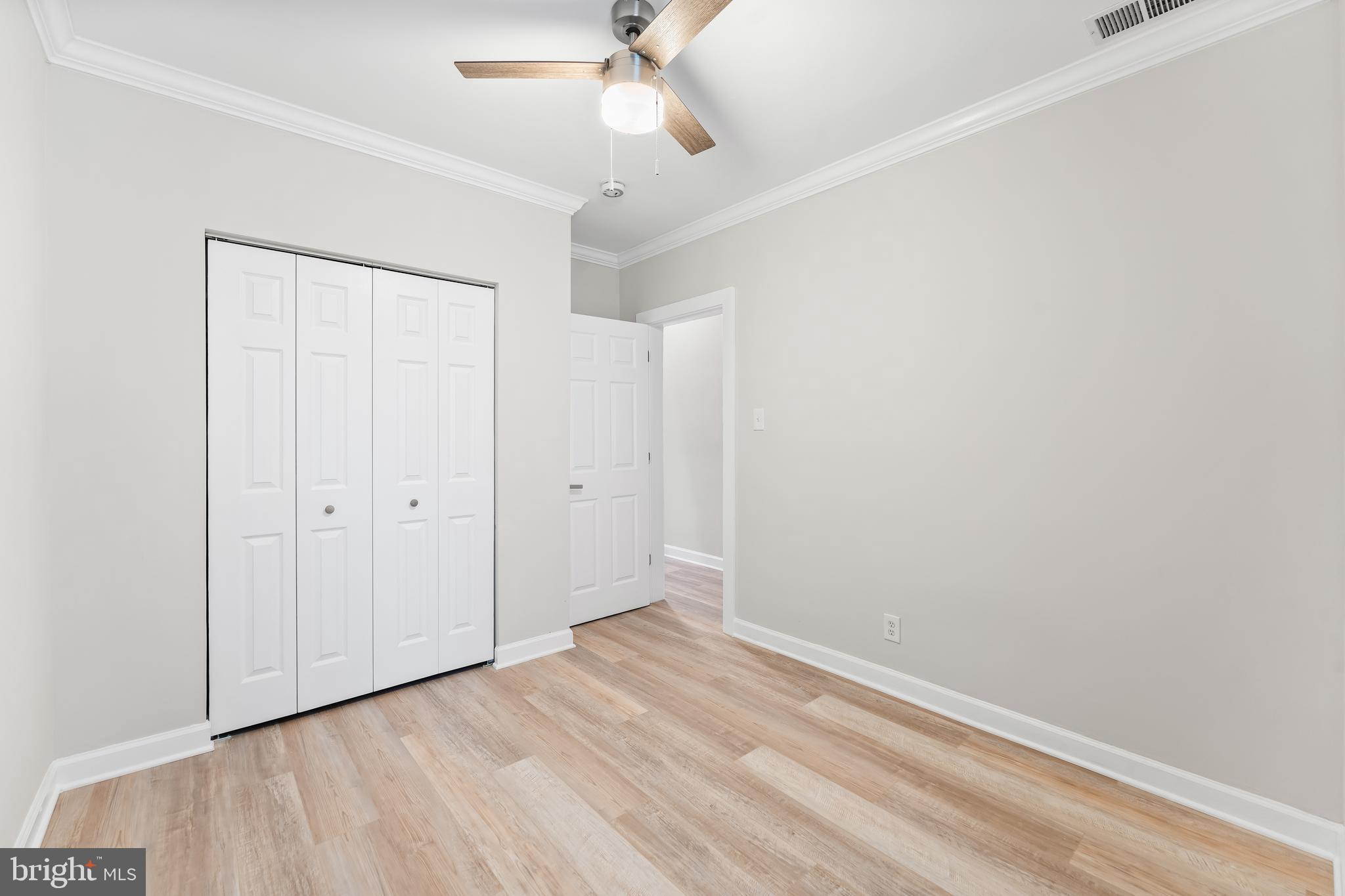 1003 West Fayette Street Baltimore, MD 21223 - Photo 23 of 59 an empty room with a ceiling fan and wooden floor