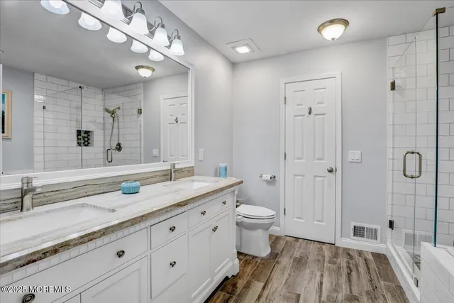 a spacious bathroom with a double vanity sink a mirror and a shower
