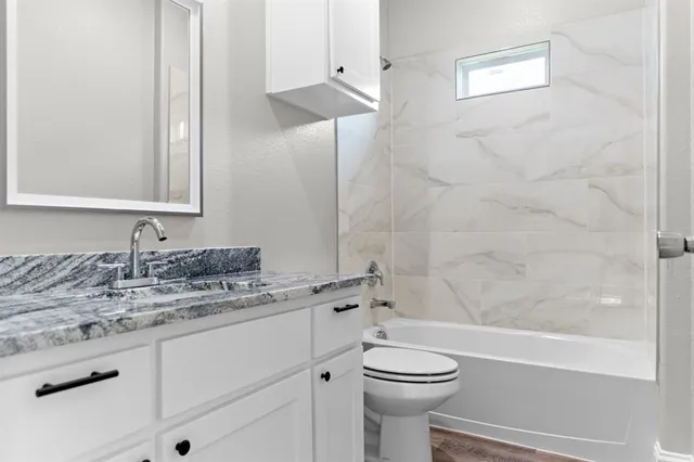 a bathroom with a granite countertop sink a toilet and bathtub