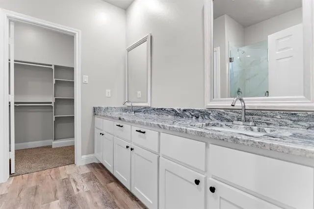 a view of a kitchen with kitchen island a sink wooden floor and stainless steel appliances