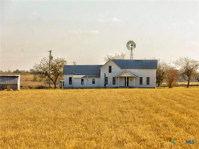 a front view of house with yard and trees in the background