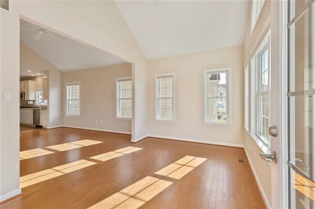 a view of an empty room with wooden floor and a window