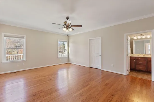 a view of an empty room with window and wooden floor