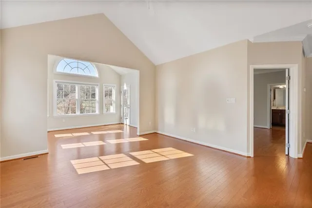 an empty room with wooden floor and windows