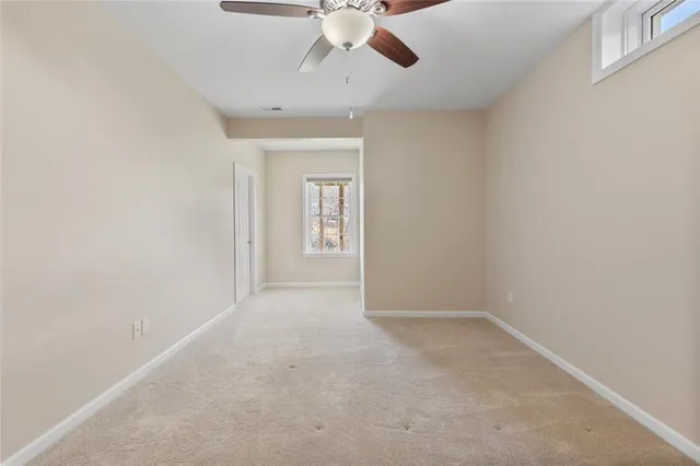 an empty room with a chandelier fan and windows
