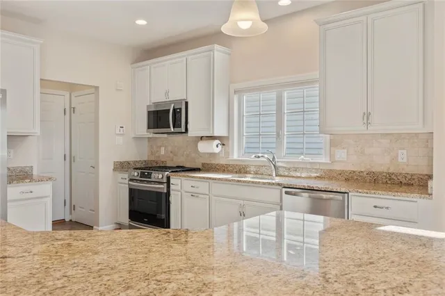 a kitchen with stainless steel appliances granite countertop a stove top oven a sink a dining table and chairs