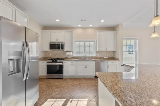 a kitchen with stainless steel appliances granite countertop a refrigerator sink and stove