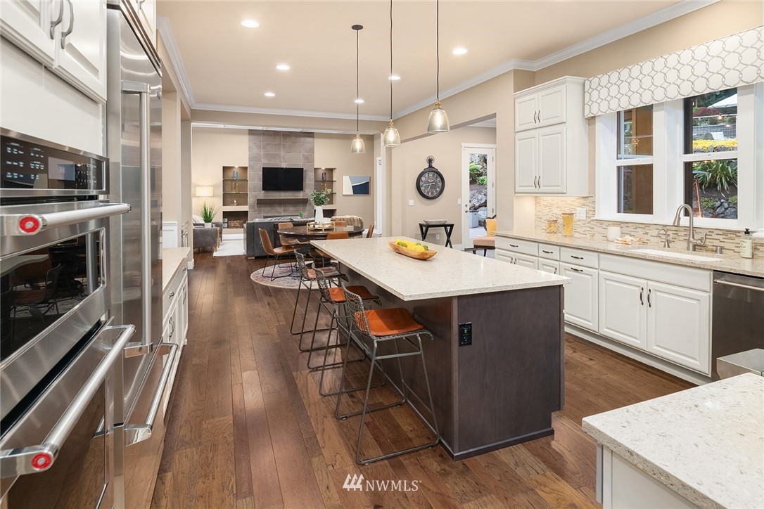 5724 197th Place Southeast Bothell, WA 98012 - Photo 15 of 40 a open kitchen with stainless steel appliances granite countertop a stove top oven a sink dishwasher a dining table and chairs with wooden floor