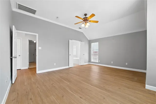 a view of an empty room with wooden floor and a ceiling fan