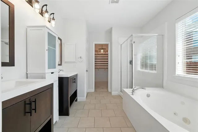 a spacious bathroom with a tub sink shower and mirror