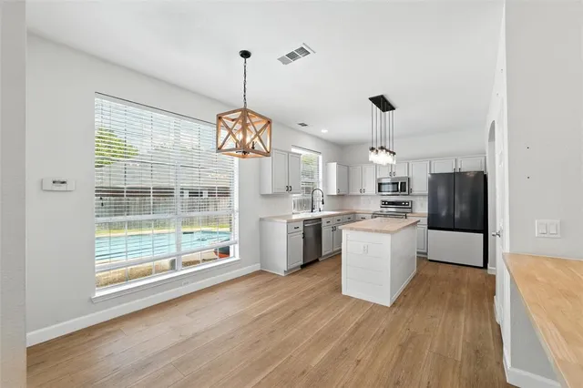 a large kitchen with a wooden floor and stainless steel appliances