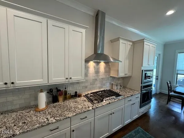 a kitchen with granite countertop a sink a stove and cabinets