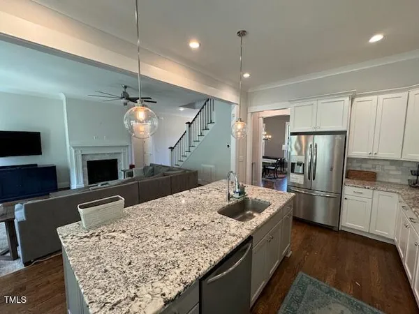 a kitchen with a refrigerator a sink dishwasher a oven with white cabinets and wooden floor