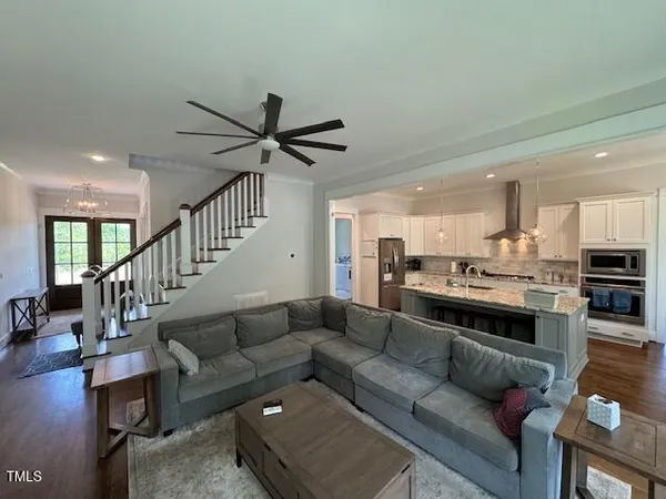 a living room with furniture kitchen view and a wooden floor
