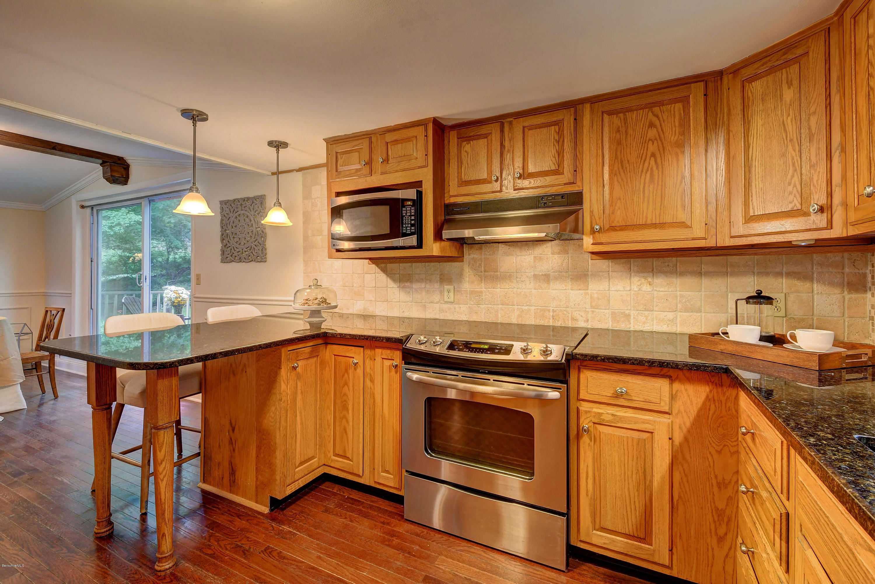 57 State Line Road West Stockbridge, MA 01266 - Photo 8 of 21 a kitchen with stainless steel appliances granite countertop wooden cabinets a sink a stove a dining table and chairs with wooden floor