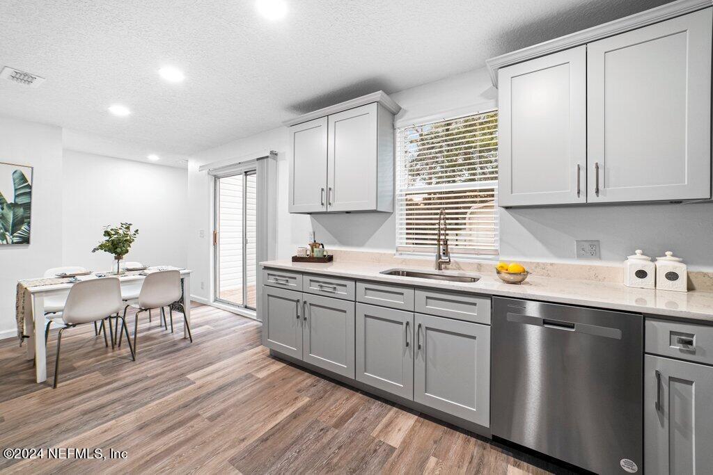 1720 Lilly Road East Jacksonville, FL 32207 - Photo 12 of 33 a kitchen with stainless steel appliances granite countertop a sink dishwasher stove and white cabinets with wooden floor