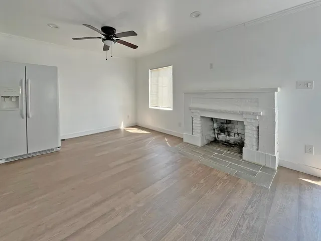 a view of empty room with wooden floor and ceiling fan