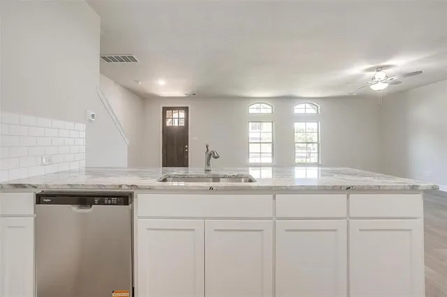 a kitchen with granite countertop kitchen island white cabinets and a chandelier