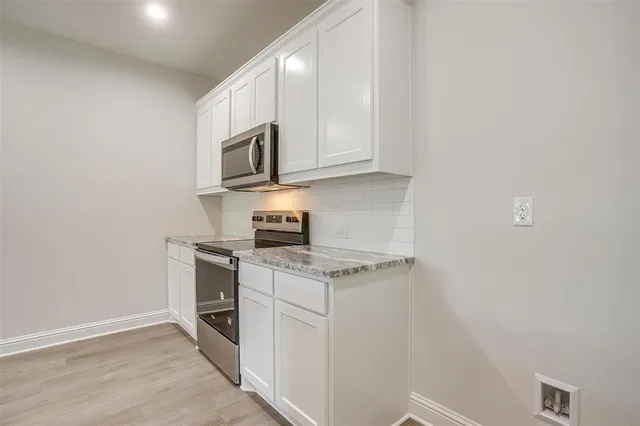 a kitchen with stainless steel appliances granite countertop a stove a sink and a microwave