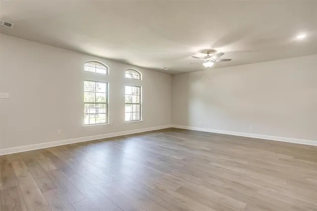 an empty room with wooden floor and window