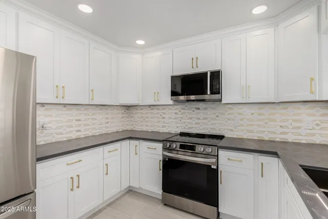 a kitchen with granite countertop white cabinets and stainless steel appliances