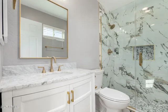 a bathroom with a granite countertop toilet sink and mirror