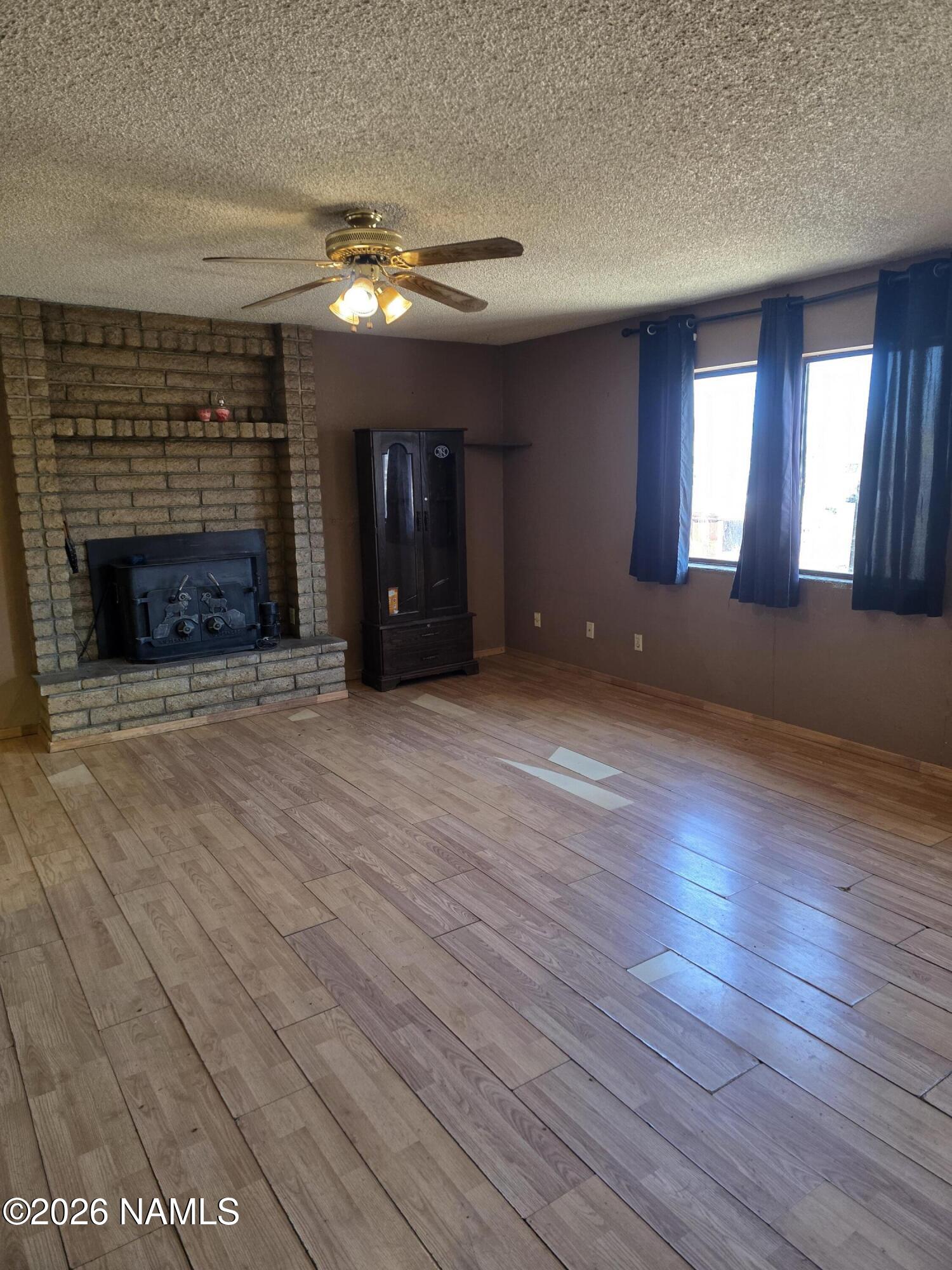 218 East Edison Avenue Williams, AZ 86046 - Photo 14 of 29 an empty room with wooden floor fireplace and windows