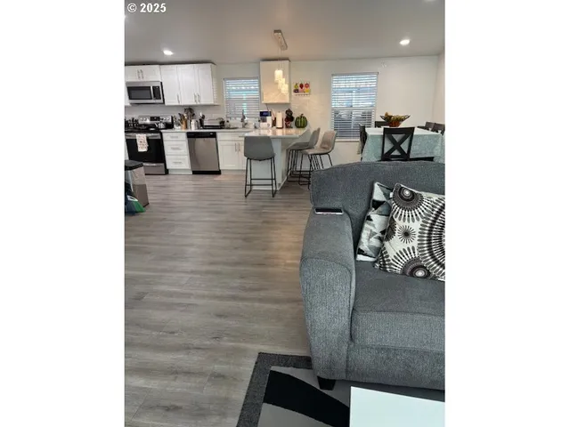 a living room with couches and kitchen view with wooden floor