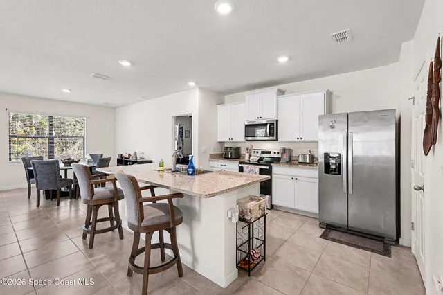a kitchen with refrigerator and chairs