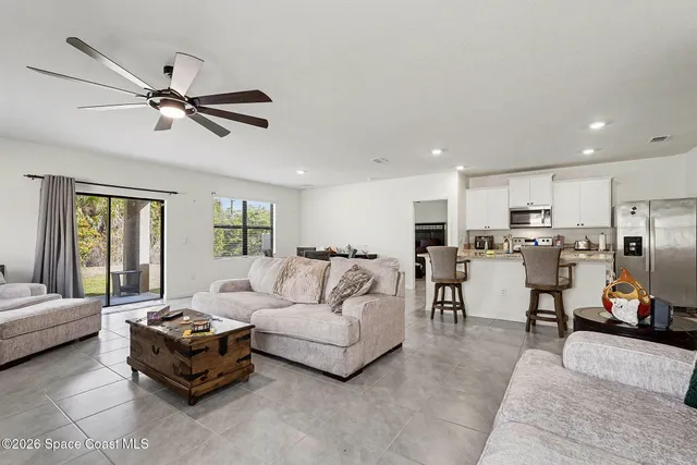 a living room with furniture kitchen view and a window