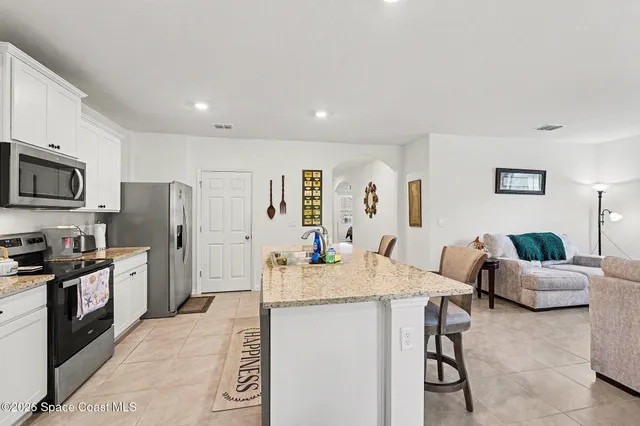 a kitchen with stainless steel appliances granite countertop a refrigerator a stove a sink a dining table and chairs