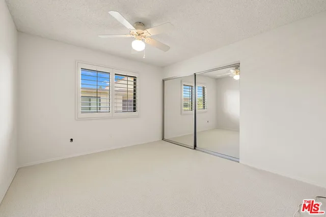 an empty room with windows and fan
