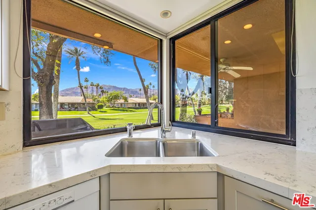 a kitchen sink with a stove and garden view