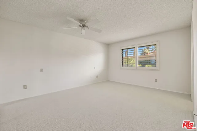 an empty room with windows and ceiling fan