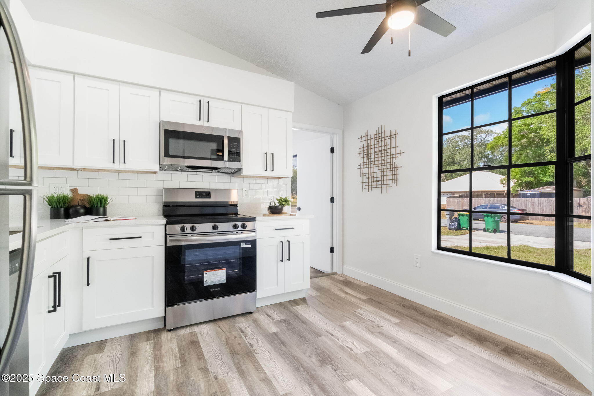 7115 Camilo Road Cocoa, FL 32927 - Photo 11 of 25 a kitchen with stainless steel appliances granite countertop a stove a microwave and white cabinets