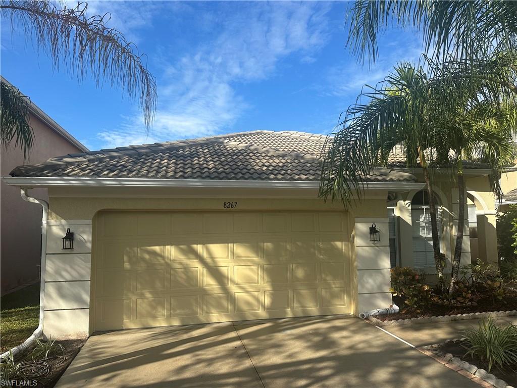 View of side of property with an attached garage, driveway, stucco siding, and a tiled roof