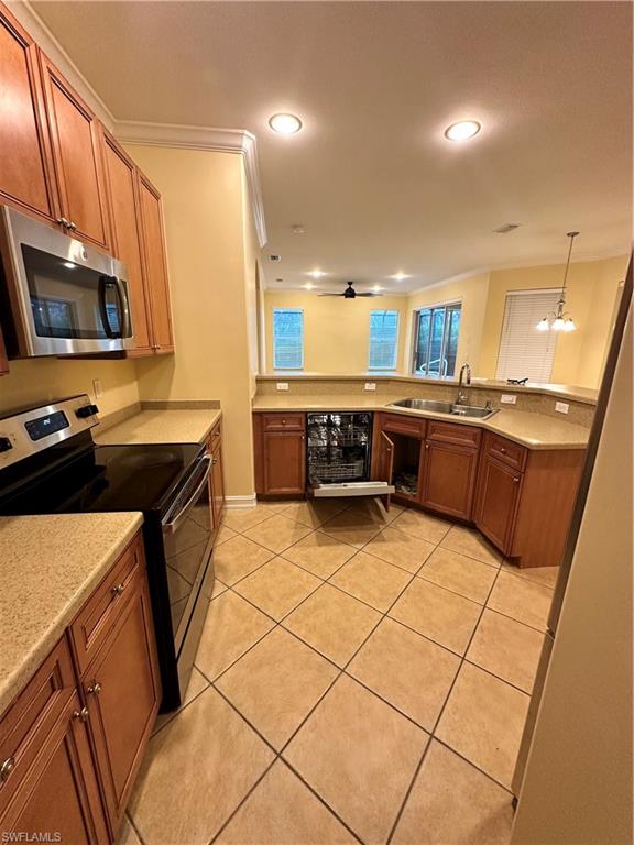 8267 Laurel Lakes Way Naples, FL 34119 - Photo 11 of 23 Kitchen with stainless steel range, brown cabinetry, light tile patterned floors, crown molding, and hanging light fixtures