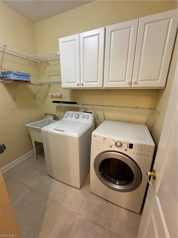 8267 Laurel Lakes Way Naples, FL 34119 - Photo 16 of 23 Laundry room featuring light tile patterned floors, cabinet space, and washer and dryer